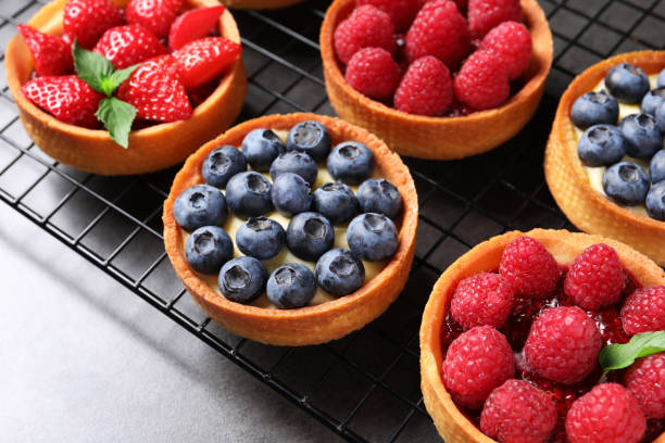 istock Tartlets with different fresh berries on grey table. Delicious dessert 1935467698
