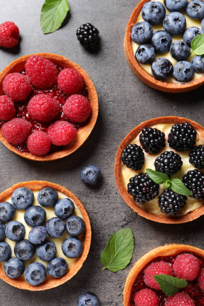 istock Tartlets with different fresh berries on grey table, flat lay. Delicious dessert 1935467699