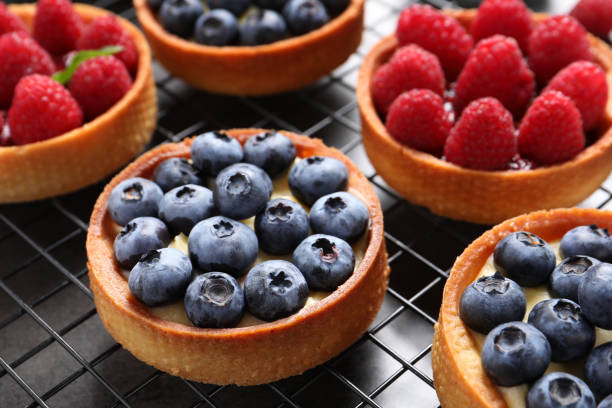 istock Tartlets with different fresh berries on cooling rack, closeup. Delicious dessert 1935468205
