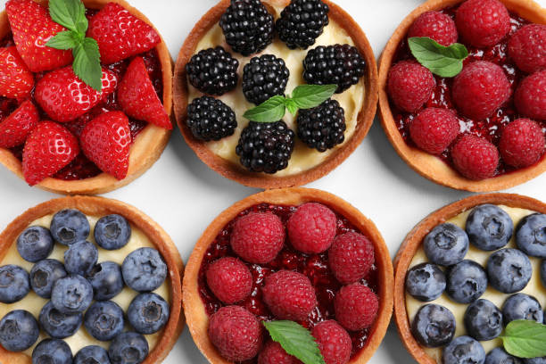 istock Tartlets with different fresh berries on white table, flat lay. Delicious dessert 1935468761