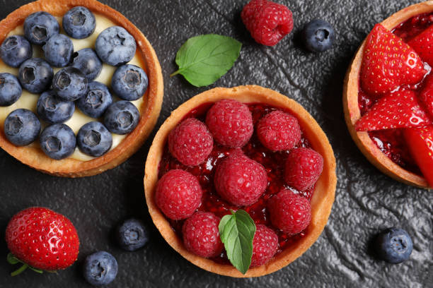 istock Tartlets with different fresh berries on black table, flat lay. Delicious dessert 1935470851