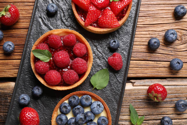 istock Tartlets with different fresh berries on wooden table, flat lay. Delicious dessert 1935470860