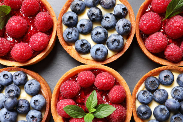istock Tartlets with different fresh berries on black table, flat lay. Delicious dessert 1935471379
