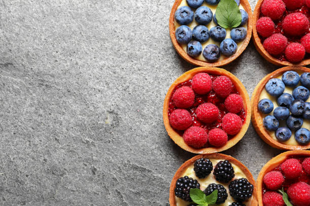 istock Tartlets with different fresh berries on light grey table, flat lay and space for text. Delicious dessert 1935471398