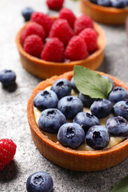 Tartlet with fresh blueberries on light grey table, closeup. Delicious dessert