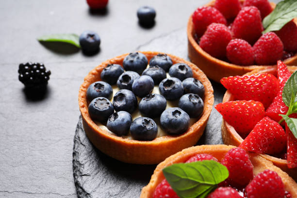 istock Tartlets with different fresh berries on black table, closeup. Delicious dessert 1935472460