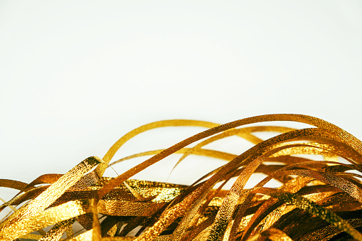 Golden shiny tinsel ribbons. Golden sequins, sparkling stripes of serpentine. Festive decor for new year, birthday, party. Background for the holiday. Heap of glowing tinsel close up