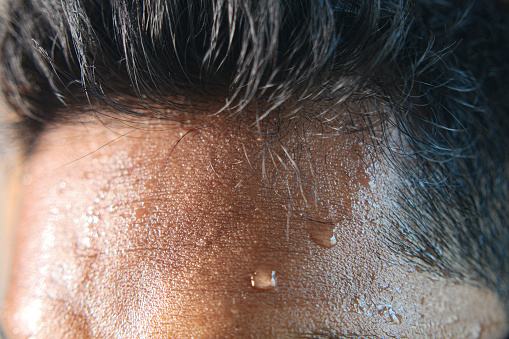 closeup of sweat on forehead against dark background