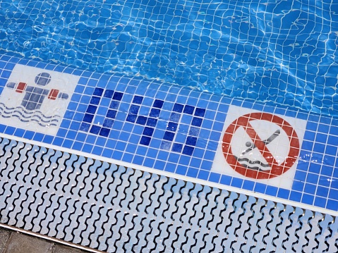 A close-up view of a pool border indicating the pool's depth and signs regulating behavior in the pool.