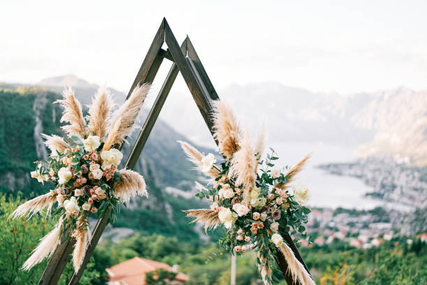 istock Triangular wedding tipi arch decorated with flowers stands on a mountain above the Kotor Bay. Montenegro 1935489459