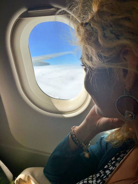 istock Happy young woman looking trough airplane window 1935503380