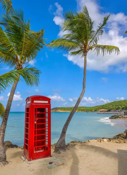 Photo of Traditional English red telephone booth on a the beach of Dickenson Bay on Antigua Island.