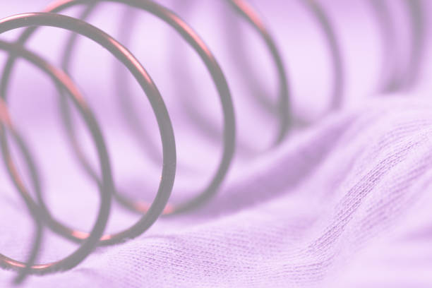 Details of a metal spring on pink cloth..