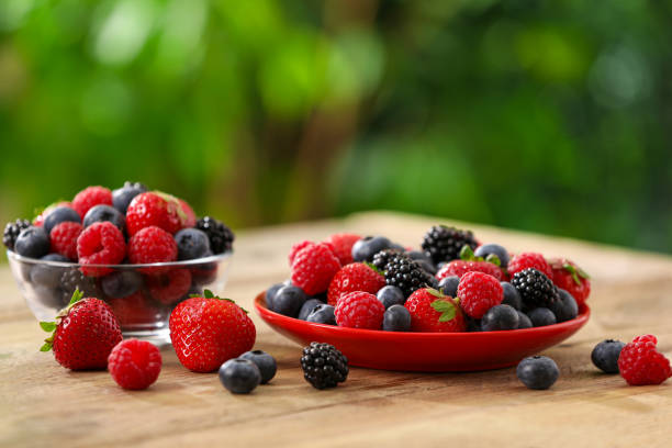 istock Different fresh ripe berries on wooden table outdoors 1935512982