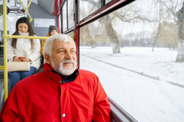 Elderly bearded man looking at window while travelling in public transport.
