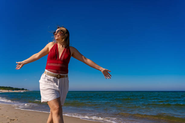 istock Beautiful woman walking on sunny beach 1935561222