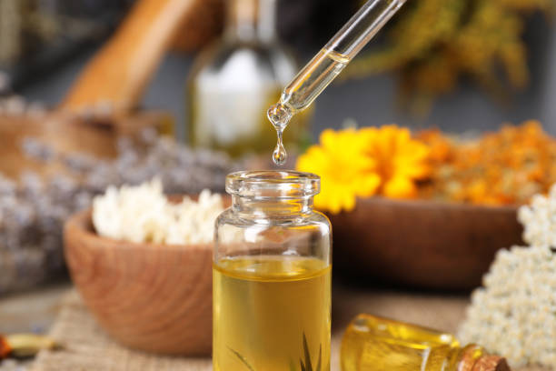 istock Dripping herbal essential oil from pipette into bottle on table, closeup 1935568653