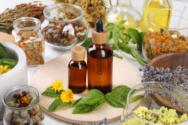 istock Bottles of essential oils surrounded by different medicinal herbs on table 1935572323