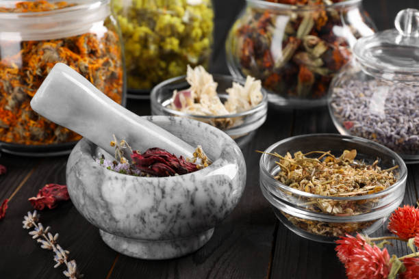 istock Mortar with pestle and many different herbs on wooden table, closeup 1935574462