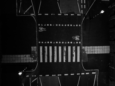 A black and white aerial photograph of a pedestrian crossing. The photograph was produced from directly above the pedestrian crossing at nighttime. The photograph was created in Manchester, Northwest England.