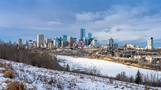 Edmonton, Canada, December 10, 2023: Cityscape with  frozen North Saskatchewan river LRT bridge and highrises on dark sky background in winter season