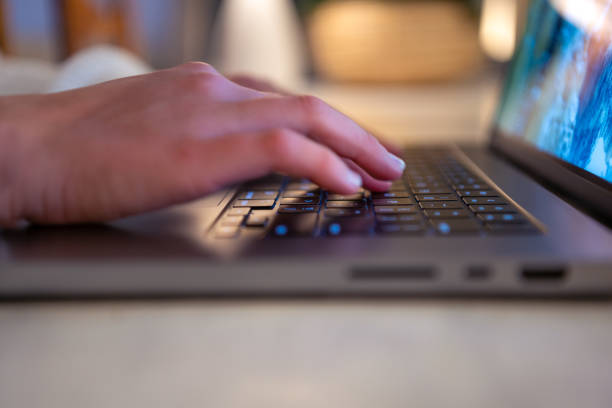 Close up of a woman’s hands typing on a laptop computer keyboard.
