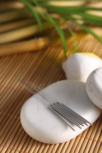 istock Acupuncture needles and spa stones on bamboo mat 1935609597