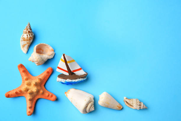 istock Beautiful starfish, decorative ship and shells on blue background, flat lay. Space for text 1935613257
