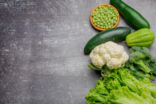 creative layout of healthy vegetables composed of lettuce, cucumbers, broccoli, green beans, peas, turnip, cabbage, chayote at gray background, copy space