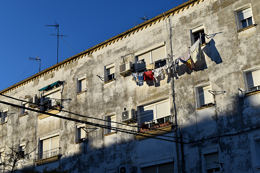 The late-day sun illuminates a block of apartments in the La Constancia neighborhood in the city of Jerez de la Frontera, some of them showing clothes hanging, air conditioning units and blinds drawn to avoid the sun