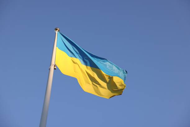 istock Flag of Ukraine fluttering against blue sky, low angle view 1935644784