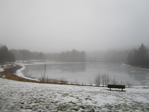 view of public park pond in early winter on a foggy morning