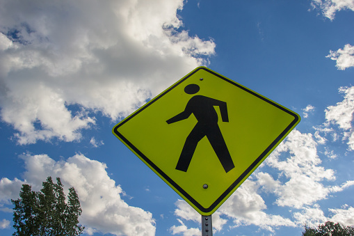 Sign indicating pedestrian crossing site at a road in a sunny day - run over risk