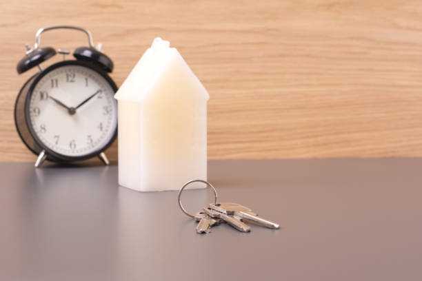 Housing tax payment deadline or mortgage loan repayment time concept. House keys with alarm clock on brown background. House keys with alarm clock on brown background. Housing tax payment deadline or mortgage loan repayment time concept. over spend stock pictures, royalty-free photos & images