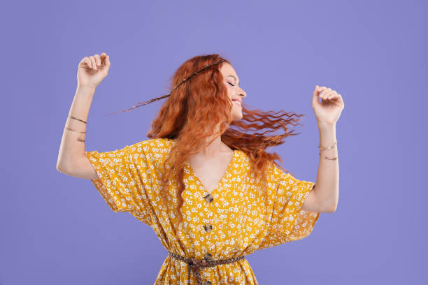 istock Beautiful young hippie woman dancing on violet background 1935674323