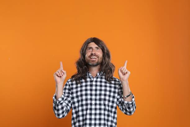 istock Hippie man pointing upwards on orange background 1935690778