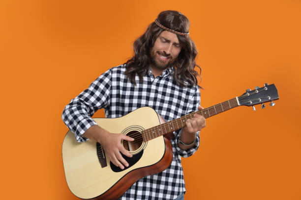 istock Hippie man playing guitar on orange background 1935692902