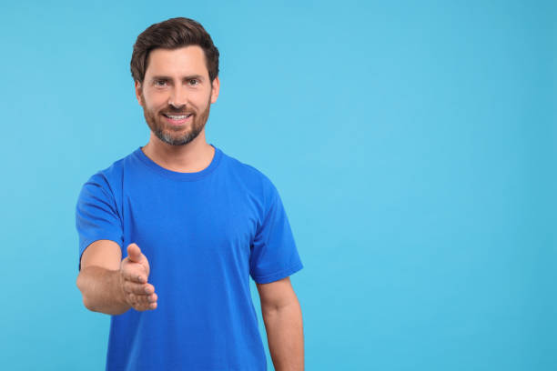 istock Happy man welcoming and offering handshake on light blue background. Space for text 1935707011
