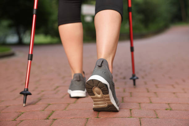 istock Young woman practicing Nordic walking with poles outdoors, back view 1935727792