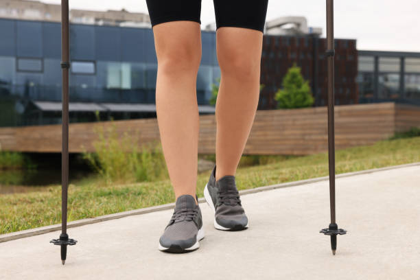 Young woman practicing Nordic walking with poles outdoors, closeup