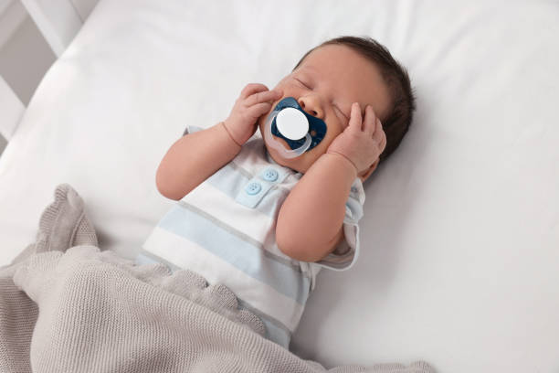 istock Cute newborn baby with pacifier sleeping under blanket in crib. Bedtime 1935734573