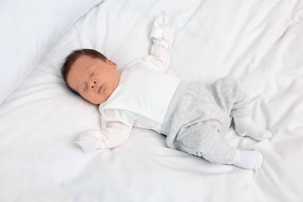 istock Cute newborn baby sleeping on white soft bed 1935734581