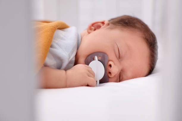 istock Cute newborn baby with pacifier sleeping on bed, closeup 1935734670