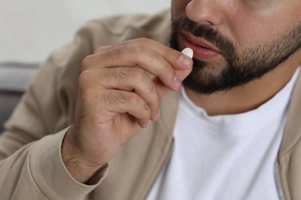 istock Man taking antidepressant pill on blurred background, closeup 1935746513