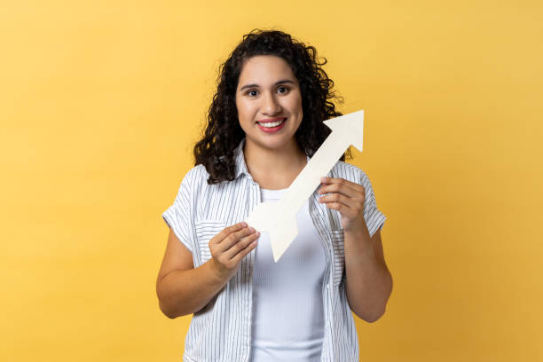 istock Woman pointing direction with arrow aside, looking at camera with positive expression. 1935821234