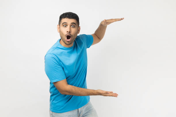 istock Shocked astonished surprised man showing advertisement area between his arms, copy space, big size. 1935823354