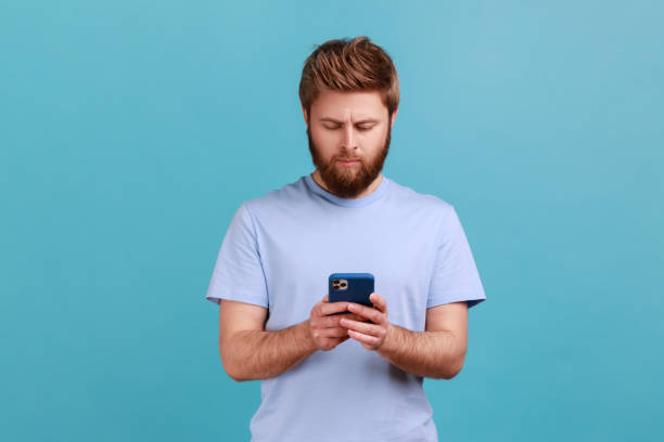 istock Man in blue T-shirt texting message in social media on cell phone, using mobile network services. 1935828079