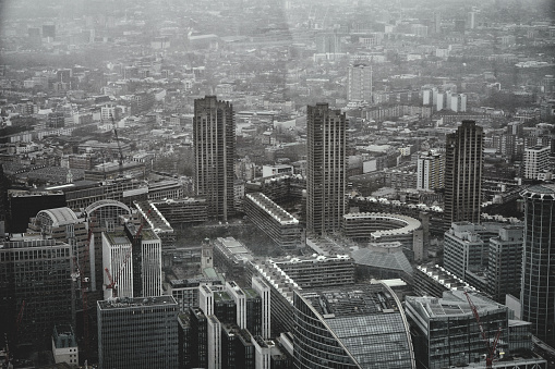 Barbican Estate, The City of London, England, United Kingdom, Great Britain - 8th of January, 2024: This aerial photograph shows a view of London from above. The photo presents the urban landscape of the city, including famous landmarks: Some features that can be seen are the Shakespeare Tower, Cromwell Tower, and Lauderdale Tower, which are part of the iconic Barbican Estate. These tall residential towers were built in the Brutalist architectural style. 

Also visible are the Golden Lane Estate and Barbican Centre arts complex. Additional points of interest in the distance include Moorgate area and views towards Bishopsgate. This  London skyline offers a glimpse of London's skyscrapers silhouetted against the winter daylight sky.

An aerial photo shot presents a panorama of the United Kingdom's capital city, London, in broad daylight. The urban landscape of London City.