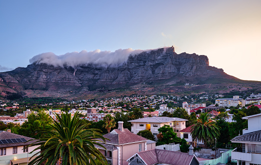 Table Mountain peak covered with cloud and suburb nestled on the foothills of Table Mountainat during sunset, Cape Town, South Africa