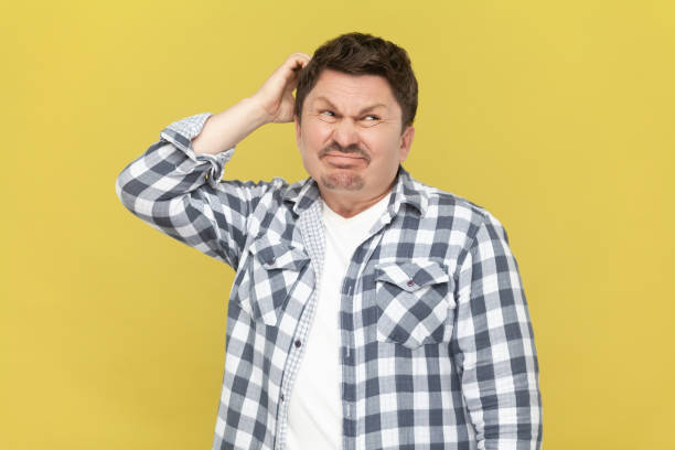 istock Thoughtful man in checkered shirt, keeps hand on his head, thinking, trying to remember something. 1935867288
